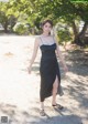 A woman in a black dress is walking down a dirt road.