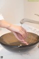 A woman washing her hands under a faucet in a bathroom sink.