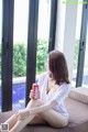 A woman sitting on a couch holding a can of soda.