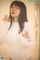 A woman in a white shirt is standing in a bathroom.