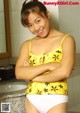 A woman in a yellow top and white panties posing for a picture.