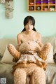 A woman sitting on a couch holding a teddy bear.