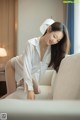 A woman in a white shirt and panties sitting on a couch.