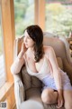 A woman sitting on a chair in front of a window.