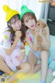 A couple of young women sitting on top of a bed with stuffed animals.