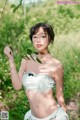 A woman in a white bikini holding a branch of a tree.