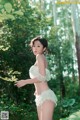 A woman in a white lingerie standing in the woods.