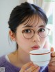 A woman wearing glasses holding a cup of coffee.