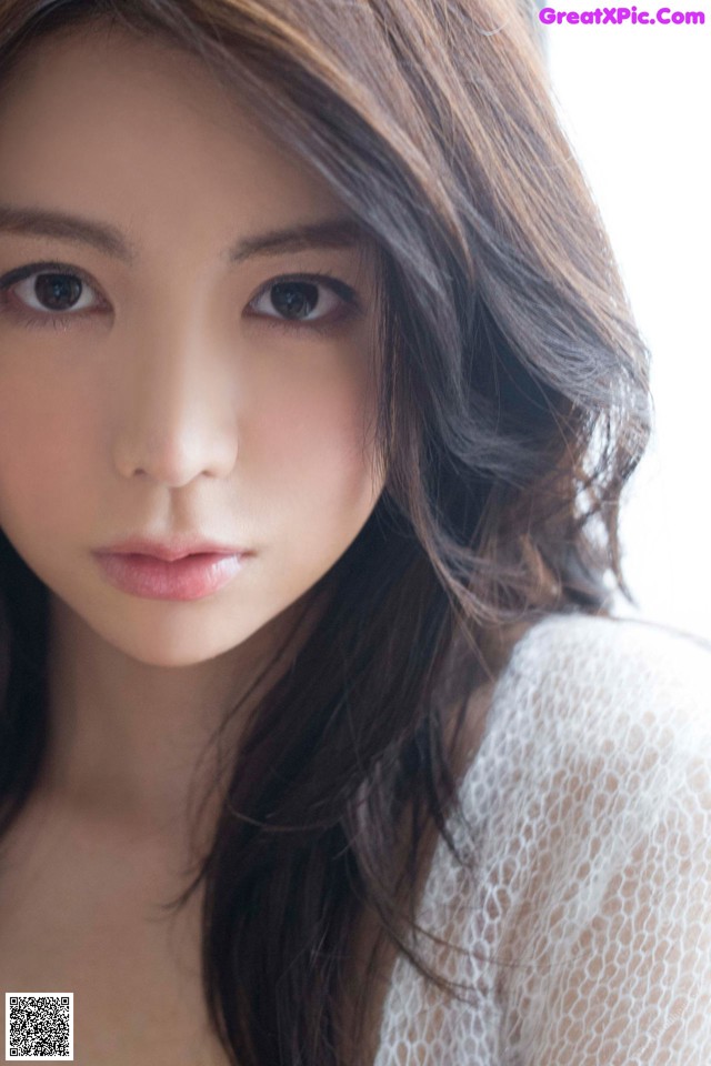 A woman with long brown hair and a white top.