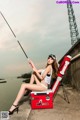 A woman sitting on a bench with a fishing rod.