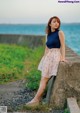 A woman leaning against a concrete wall by the ocean.