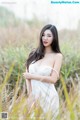 A woman in a white dress standing in tall grass.