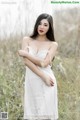 A woman in a white dress standing in tall grass.