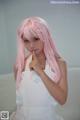 A woman with long pink hair wearing a white dress.