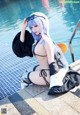 A woman in a bikini sitting by a swimming pool.