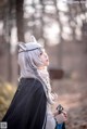 A woman with long white hair wearing a cat ears headband.