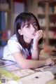 A young woman sitting at a table with a book.