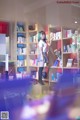 A woman standing in front of a book shelf filled with books.