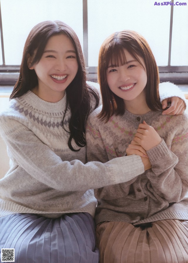 Two young women sitting next to each other on a window sill.