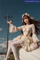 A woman in a white dress sitting on a pole.