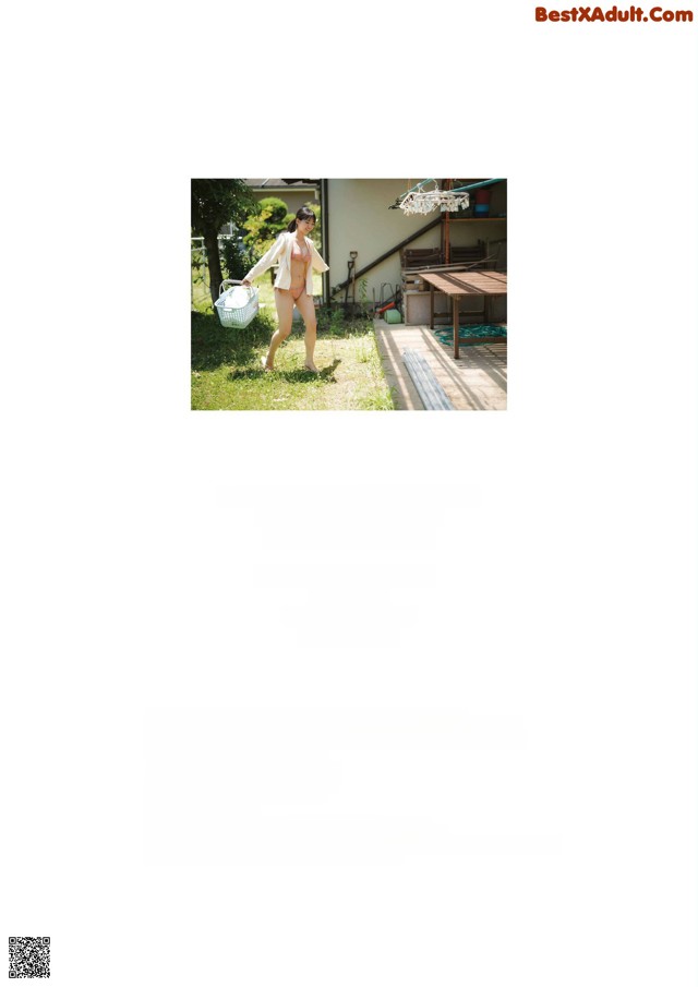 A woman in a bikini is walking in the grass.