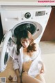 A woman sitting in front of a washing machine.